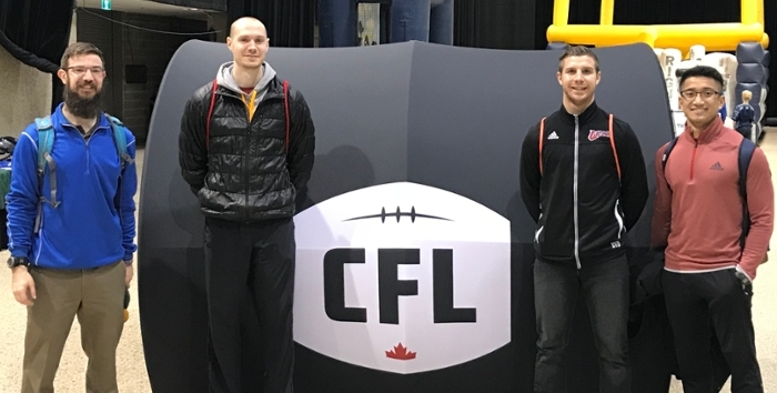 Four Kinesiology Students with CFL sign in the RecPlex field house.