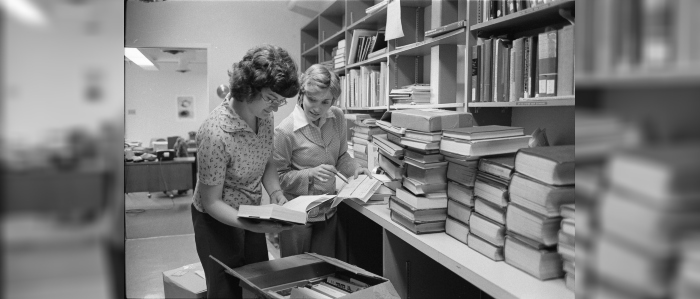 Black and white photo of students flipping through book