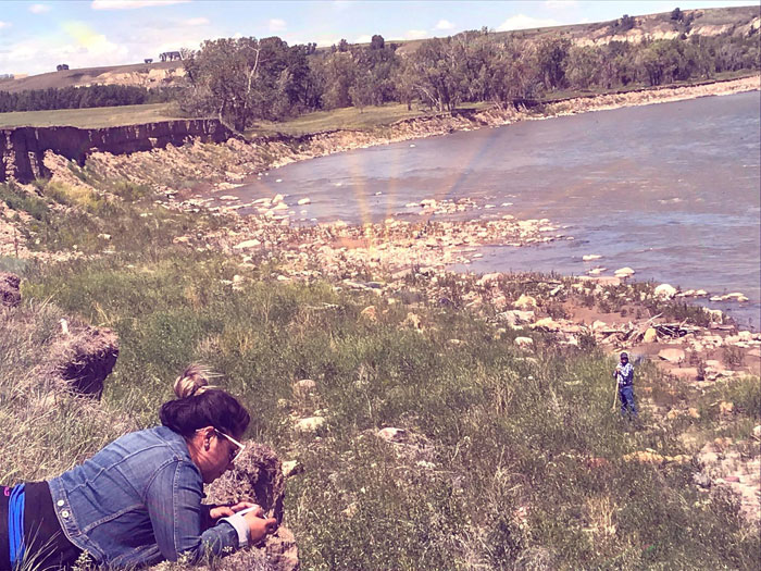 Chelsie receiving teachings from Blackfoot Elder Mike Bruisehead at the sacred Buffalo Jump site