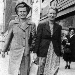 Black and white photo of two women walking down a city street