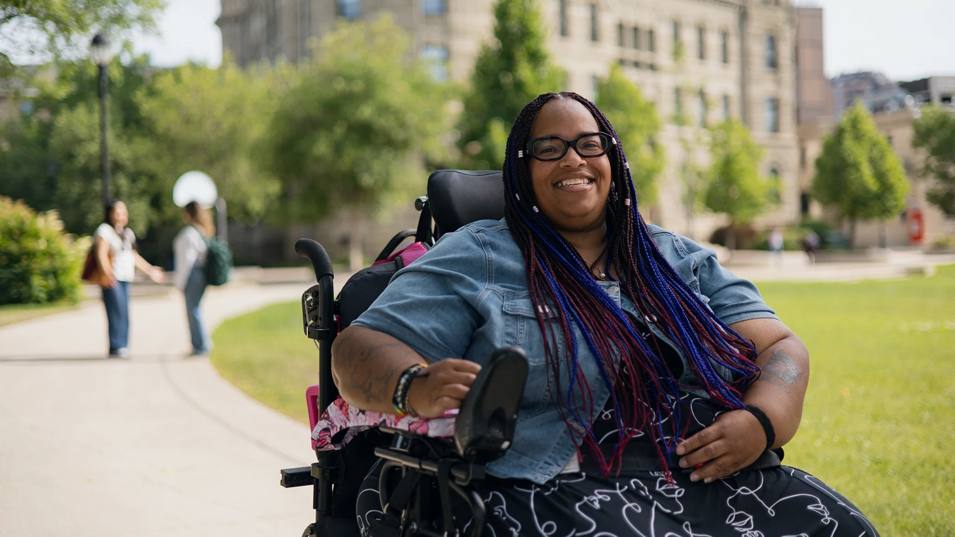 Student in a wheelchair in front of Wesley Hall smiling at the camera