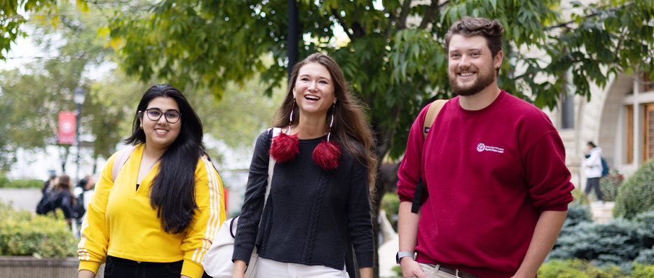 Three students sitting on front lawn of campus