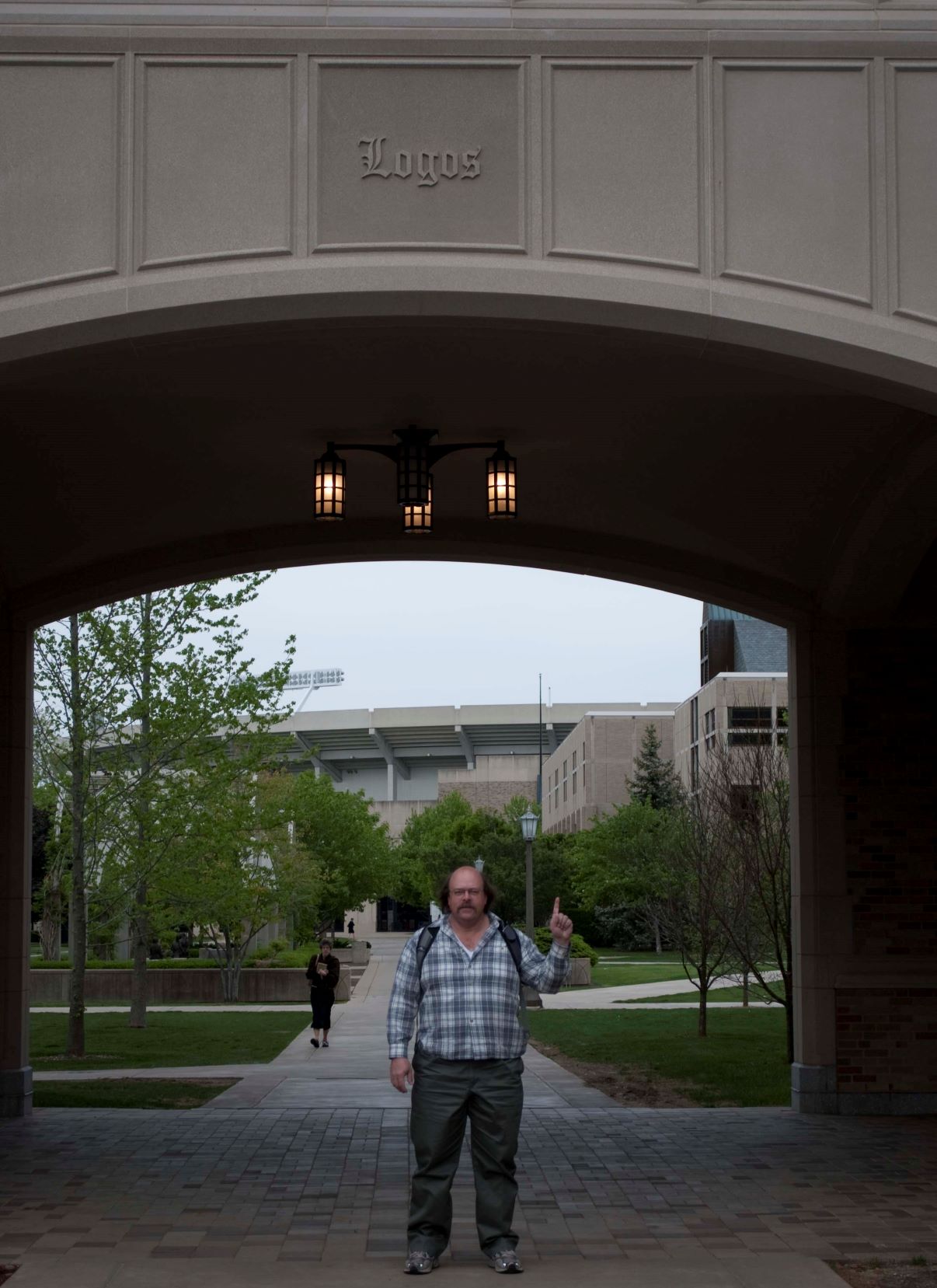 "Logos and the One": Dr. James Muir, standing under arch which reads "Logos"