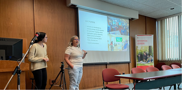 A professor and student presenting a project on a screen with powerpoint..