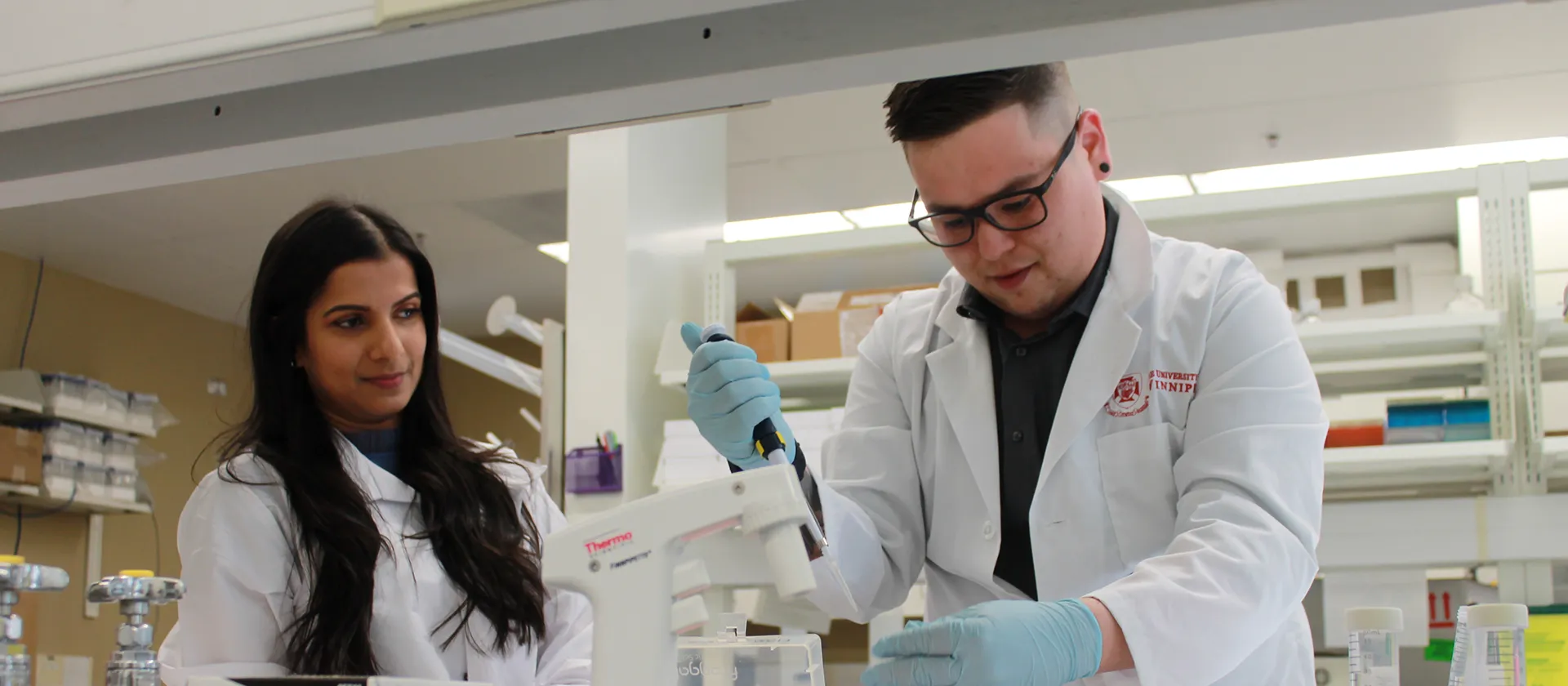 Two people in lab coats working in a lab.