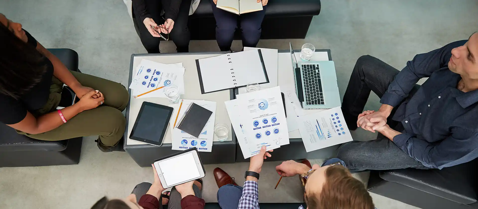 People sitting around a desk looking at papers and graphs - image is taken from above