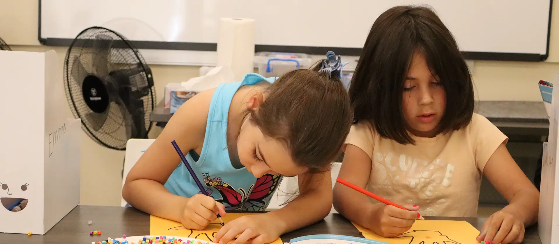 Two children at a desk drawing pictures