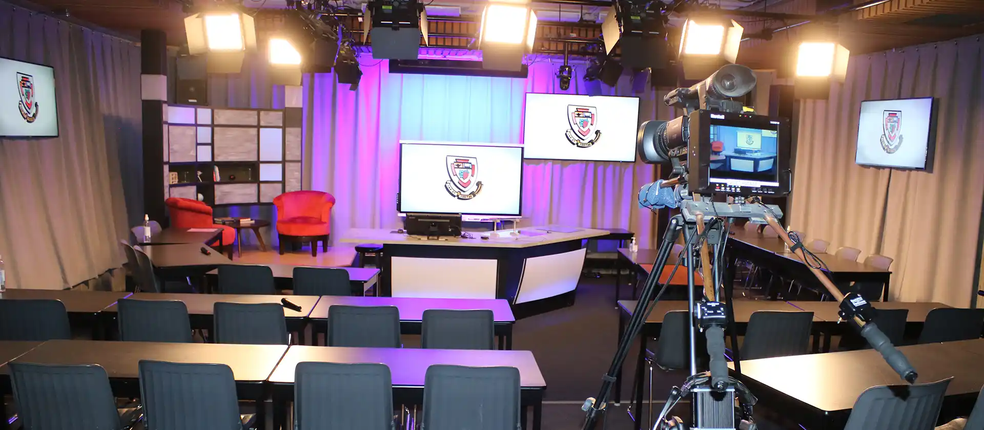 Studio set up with a camera at the back facing two empty red chairs at the front