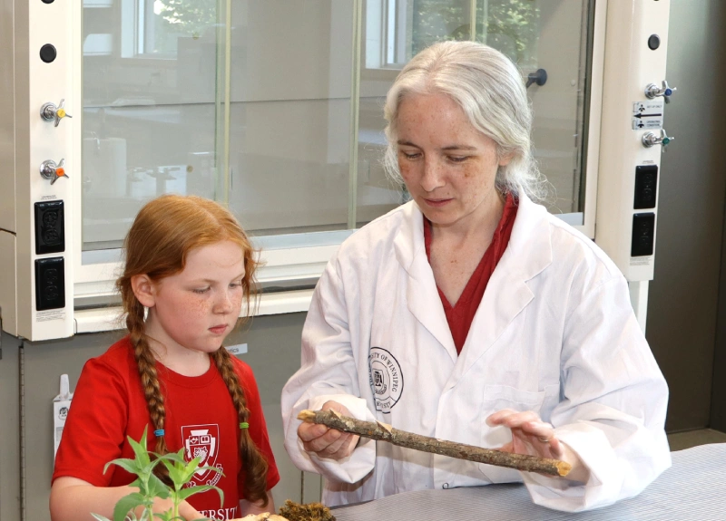 Young girl and professor in lab examining tree bark