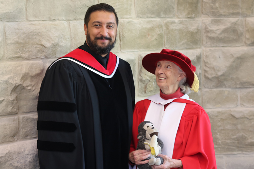 Carlos Colorado in regalia standing front of a stone wall with Jane Goodall. 