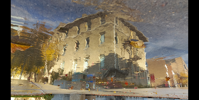 Rippled reflection of a building in a puddle