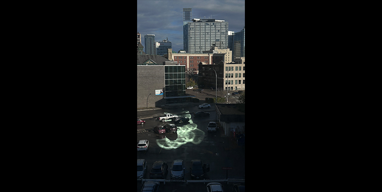 View of city buildings and a parking lot, with a circular cluster of light reflection in the centre