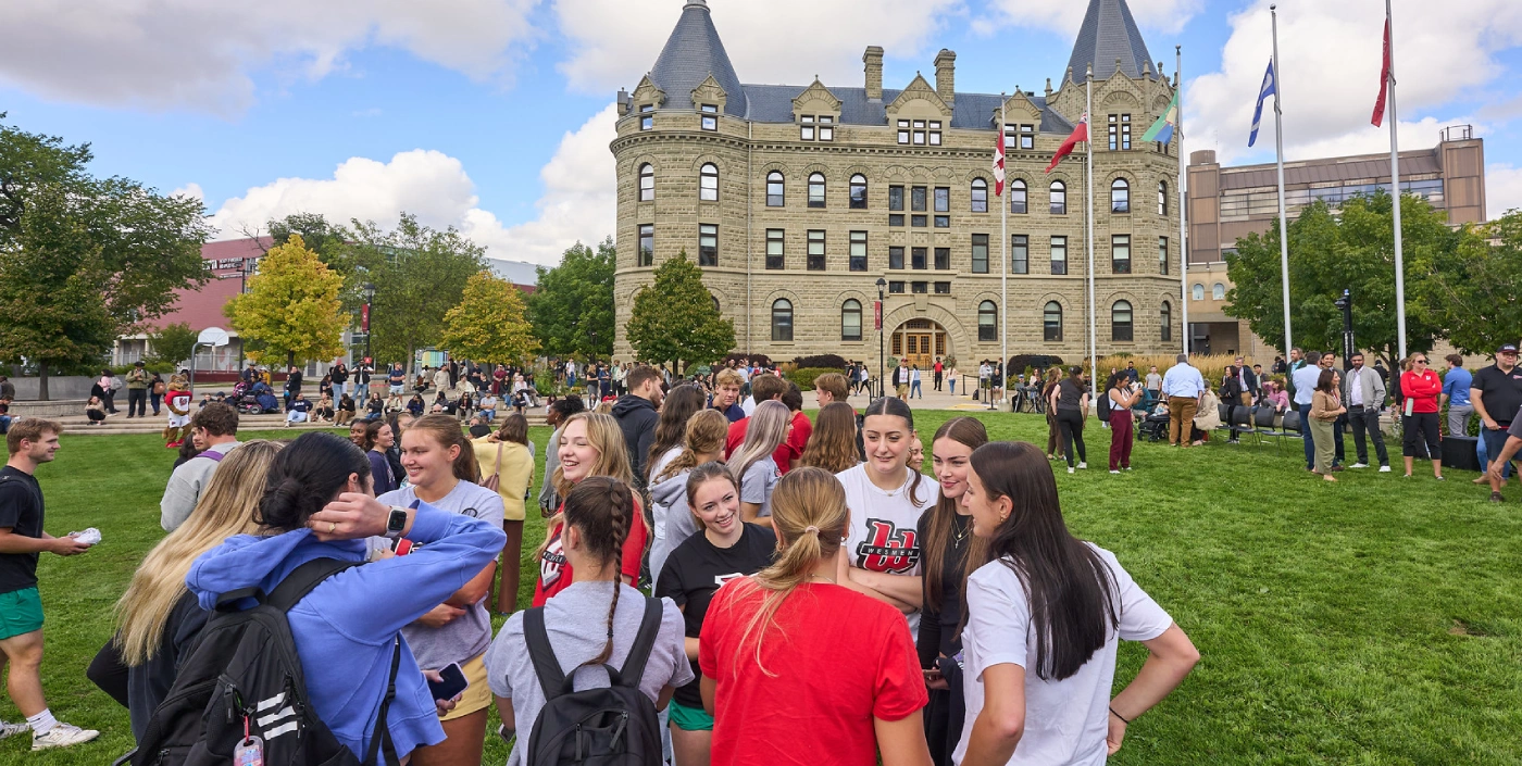 Students stand in a large group on the front lawn in front of Wesley Hall