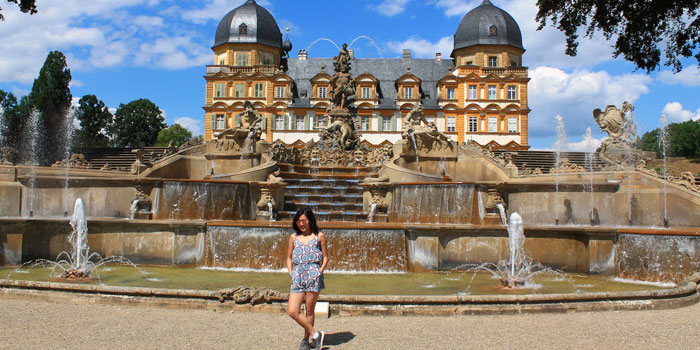 Beatrice Tuano standing in front of fountains and Schloss Seehof (palace)