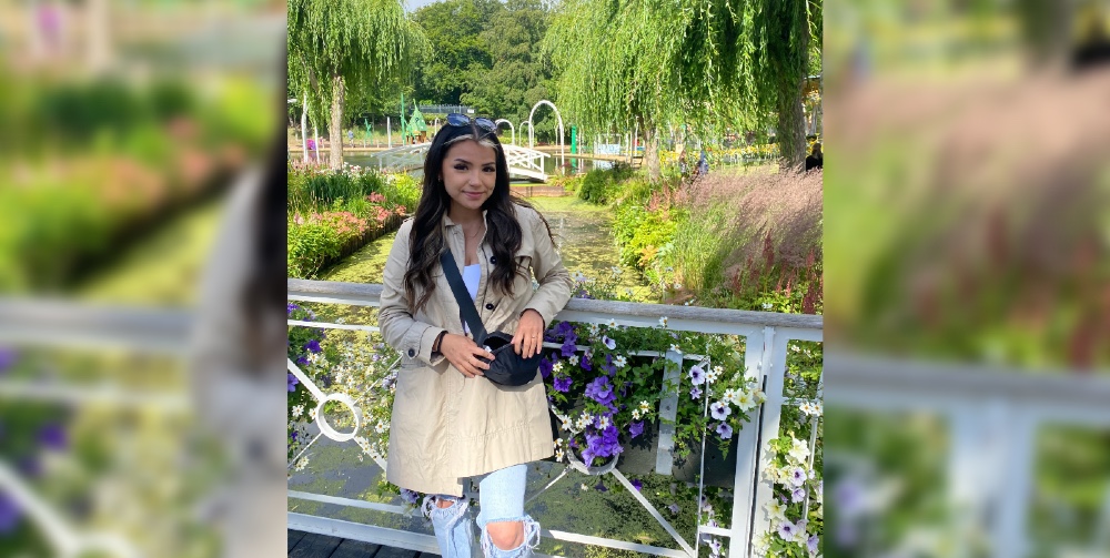 Jade standing on a footbridge in front of a garden