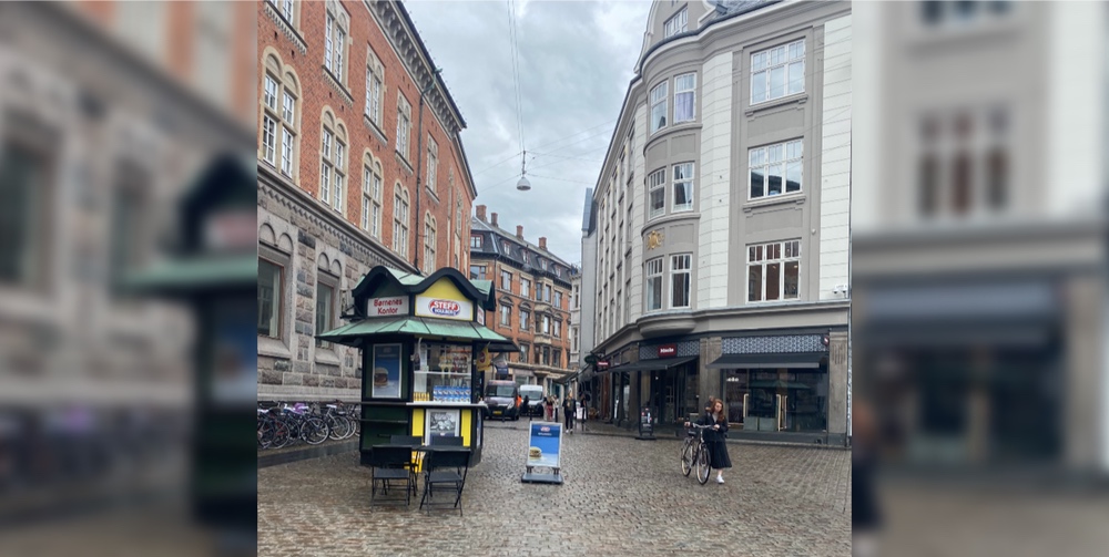 A stand in a cobblestoned city square with apartment housing in the background surroundings