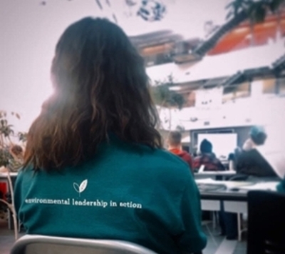 The back of an Eco team members head with a t-shirt that reads "Environmental leadership in action." 