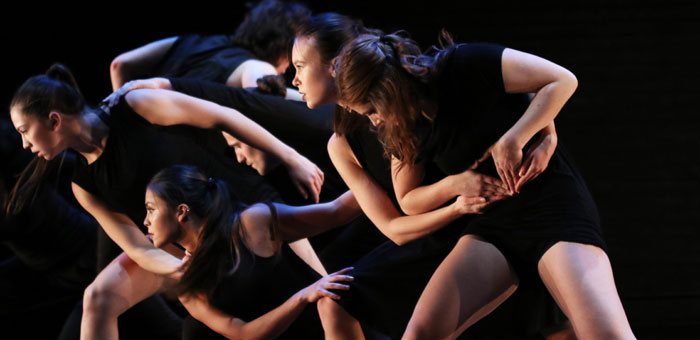 Several dancers in black intertwined