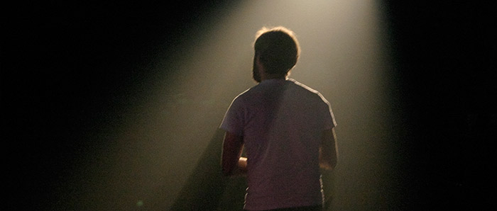 An actor silhouetted in a spotlight