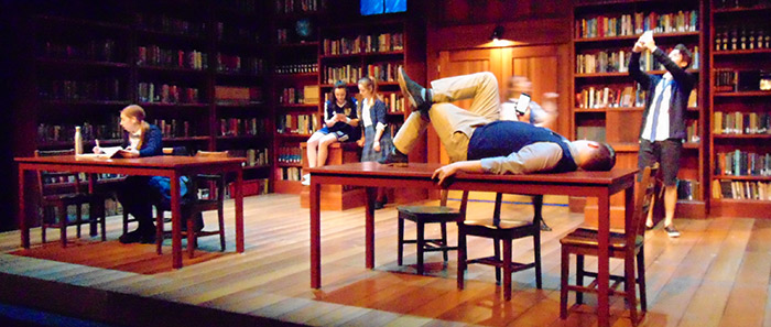 Actors lounging on a set that looks like a library