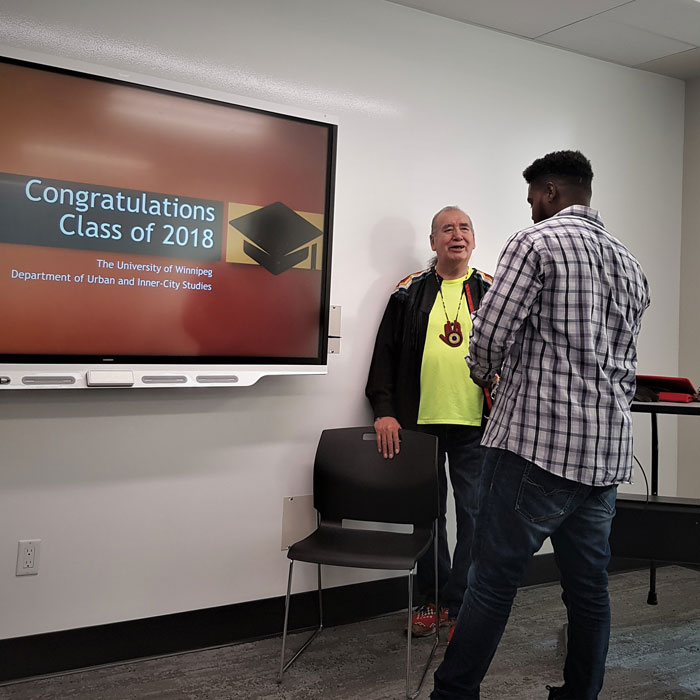 Abraham Eyob receiving an Eagle feather from UIC Elder Calvin Pompana