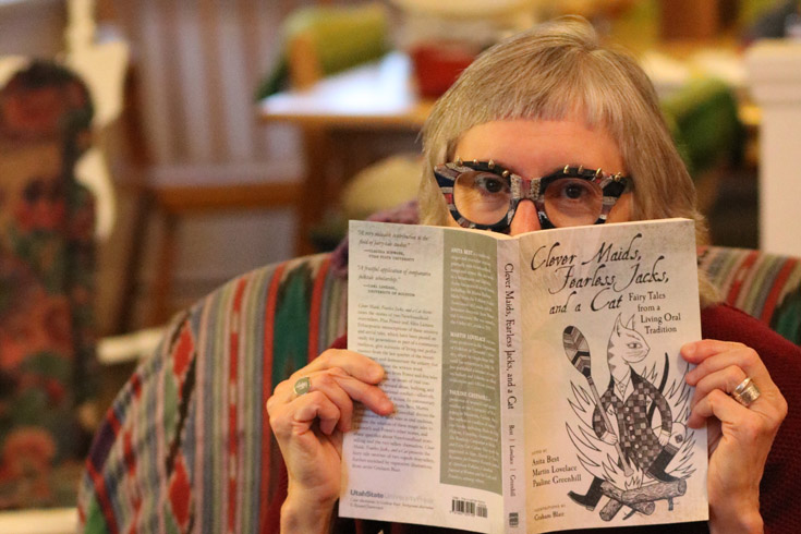 Dr. Pauline Greenhill holding up copy of her 2019 book, Clever Maids, Fearless Jacks, and a Cat